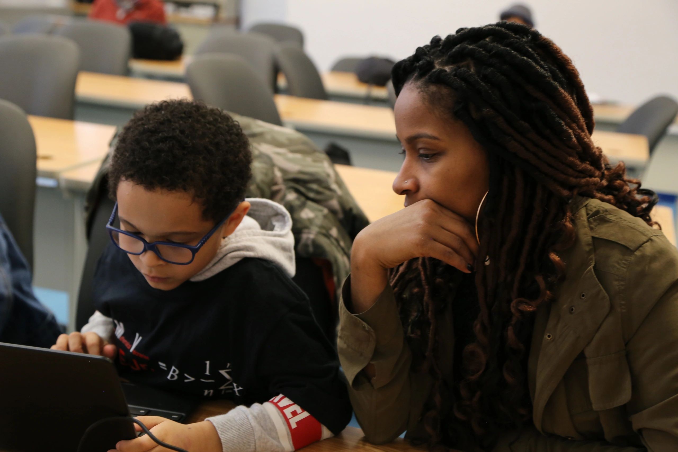 An instructor helping a young student learn computer science at a computer during a prior Microsoft Code Academy program